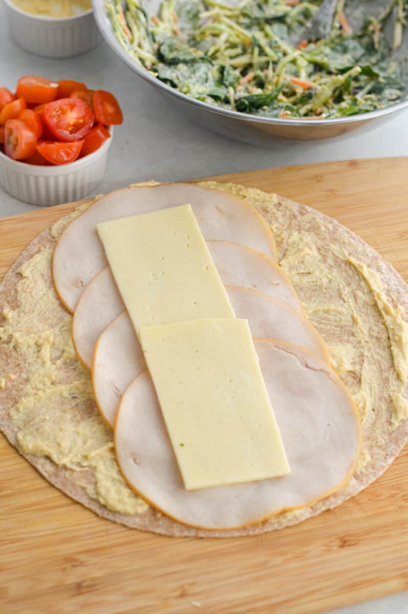 Layering deli chicken slices and havarti cheese on tortilla.