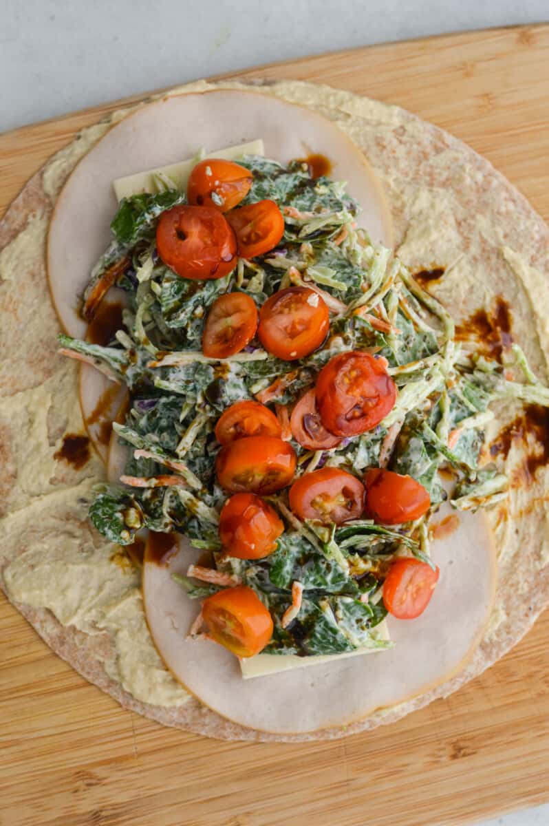 Filling wrap with pesto spinach slaw, cherry tomatoes and balsamic glaze.
