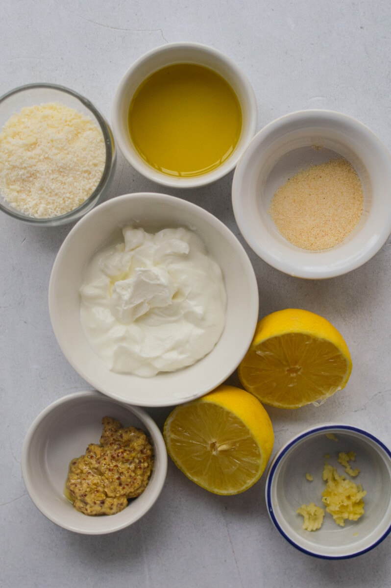 Ingredients including Greek yogurt, lemons, dijon mustard, olive oil, parmesan cheese, and garlic.