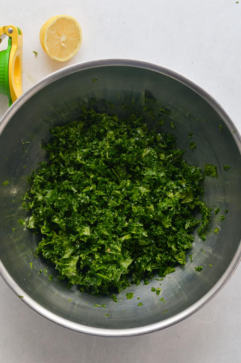 Massaging chopped kale with olive oil and lemon juice.