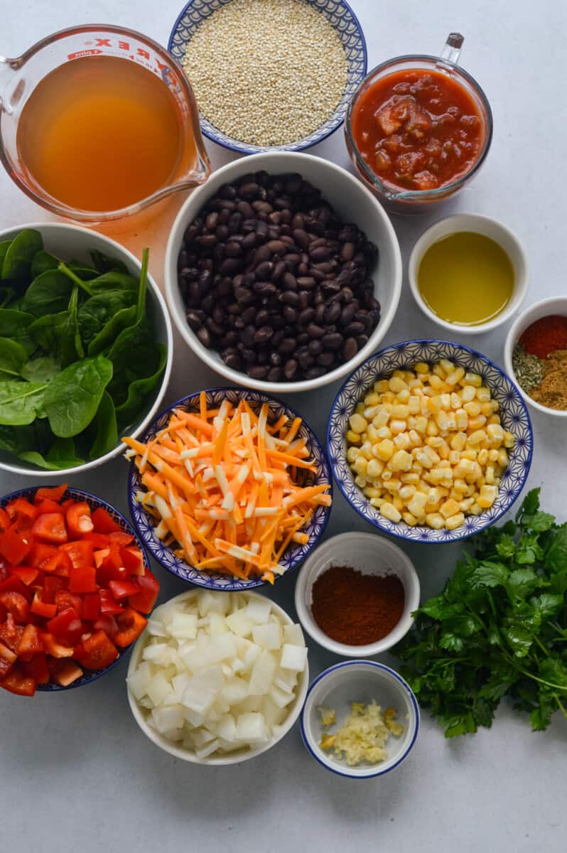 Ingredients including quinoa, black beans, cheese, corn, spices, onion, red bell pepper, cilantro, broth, salsa and spinach.
