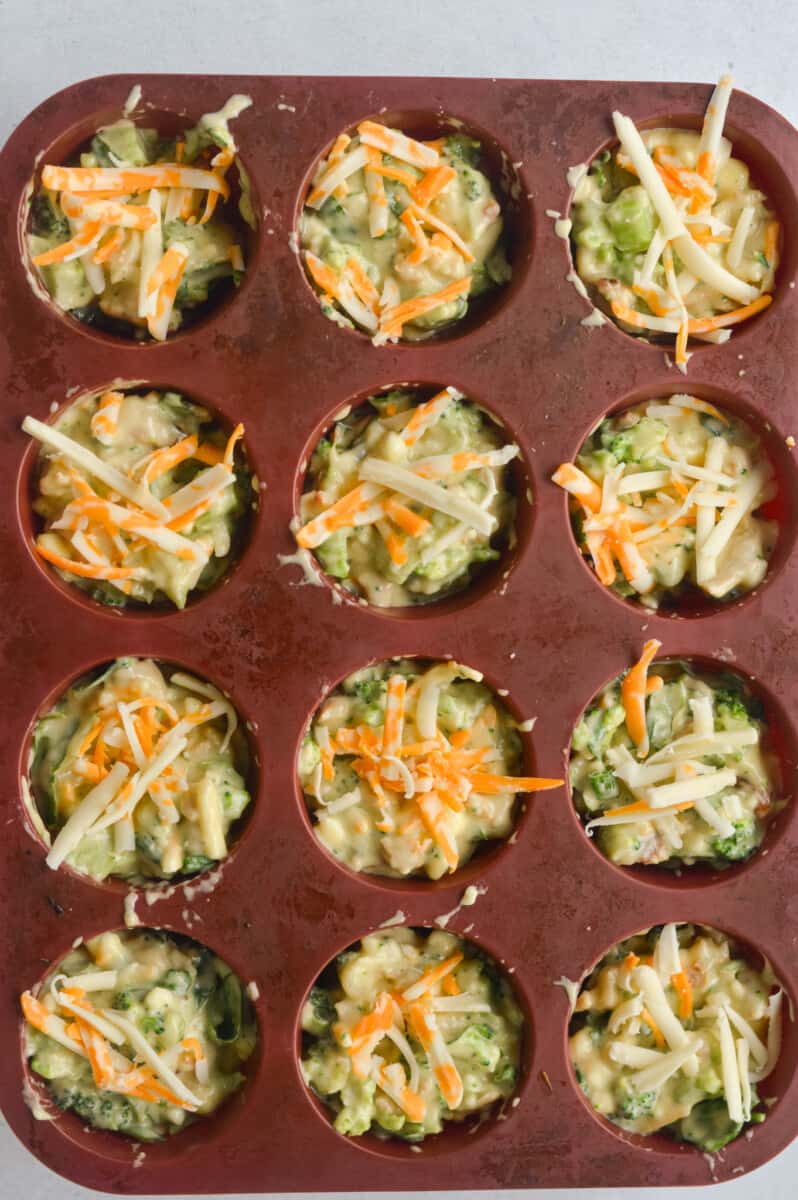 Topping cottage cheese muffins with shredded cheese.