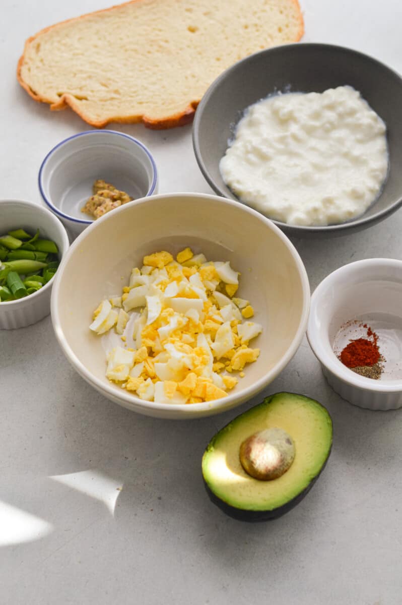 Ingredients including bread, avocado, egg, cottage cheese, Dijon mustard, green onion and spices.