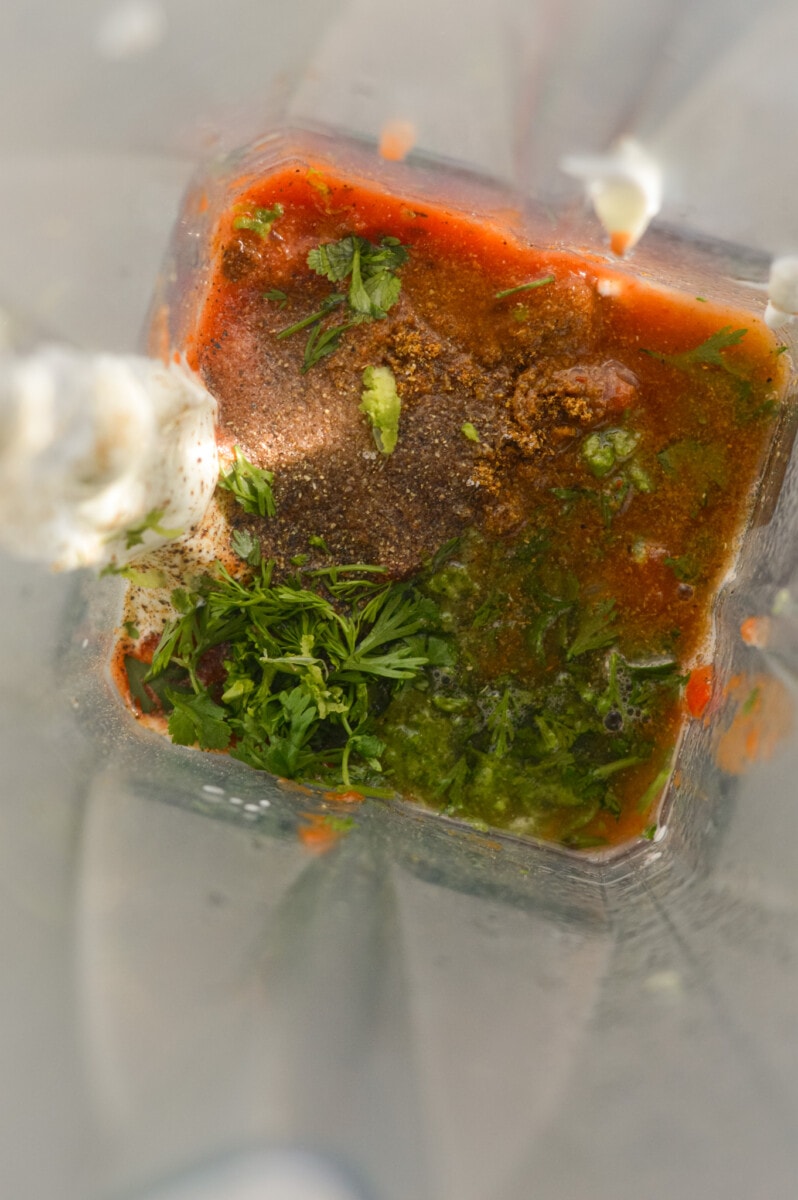 Adding salsa, Greek yogurt, cilantro, seasoning and lime to a blender.