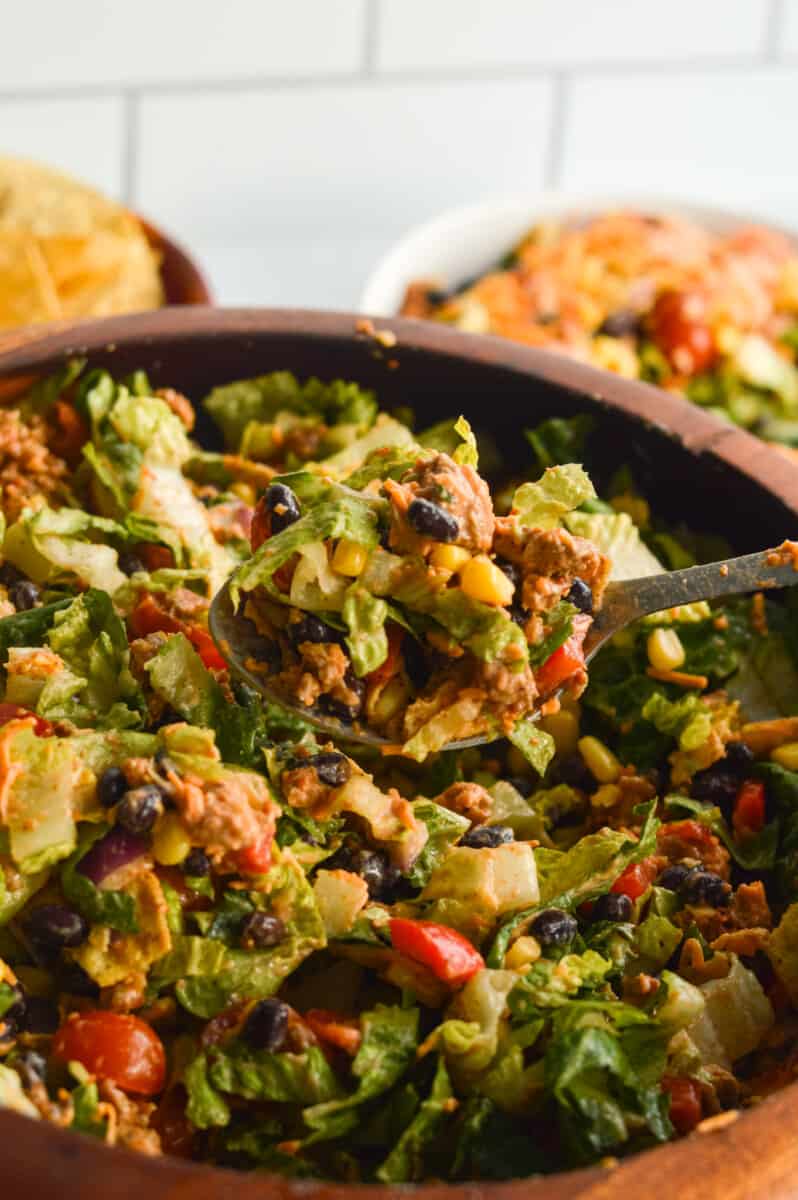 Tossing nacho salad in a brown bowl.
