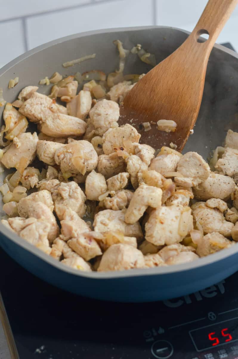 Cooking chicken breast pieces, shallots and garlic in a pan.