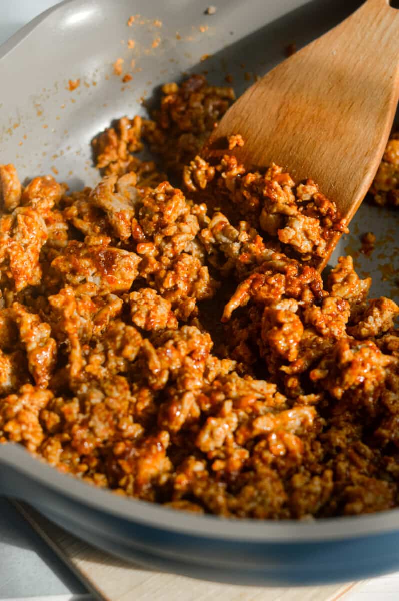 Cooking ground turkey with taco seasoning in a pan.