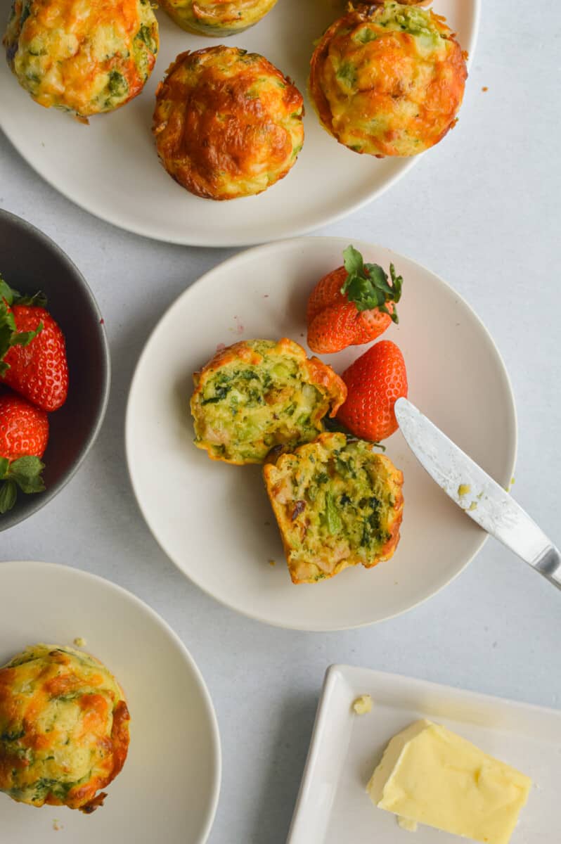 Birds eye of table with a plate of cottage cheese muffins and a plate with a muffin cut in half with berries.