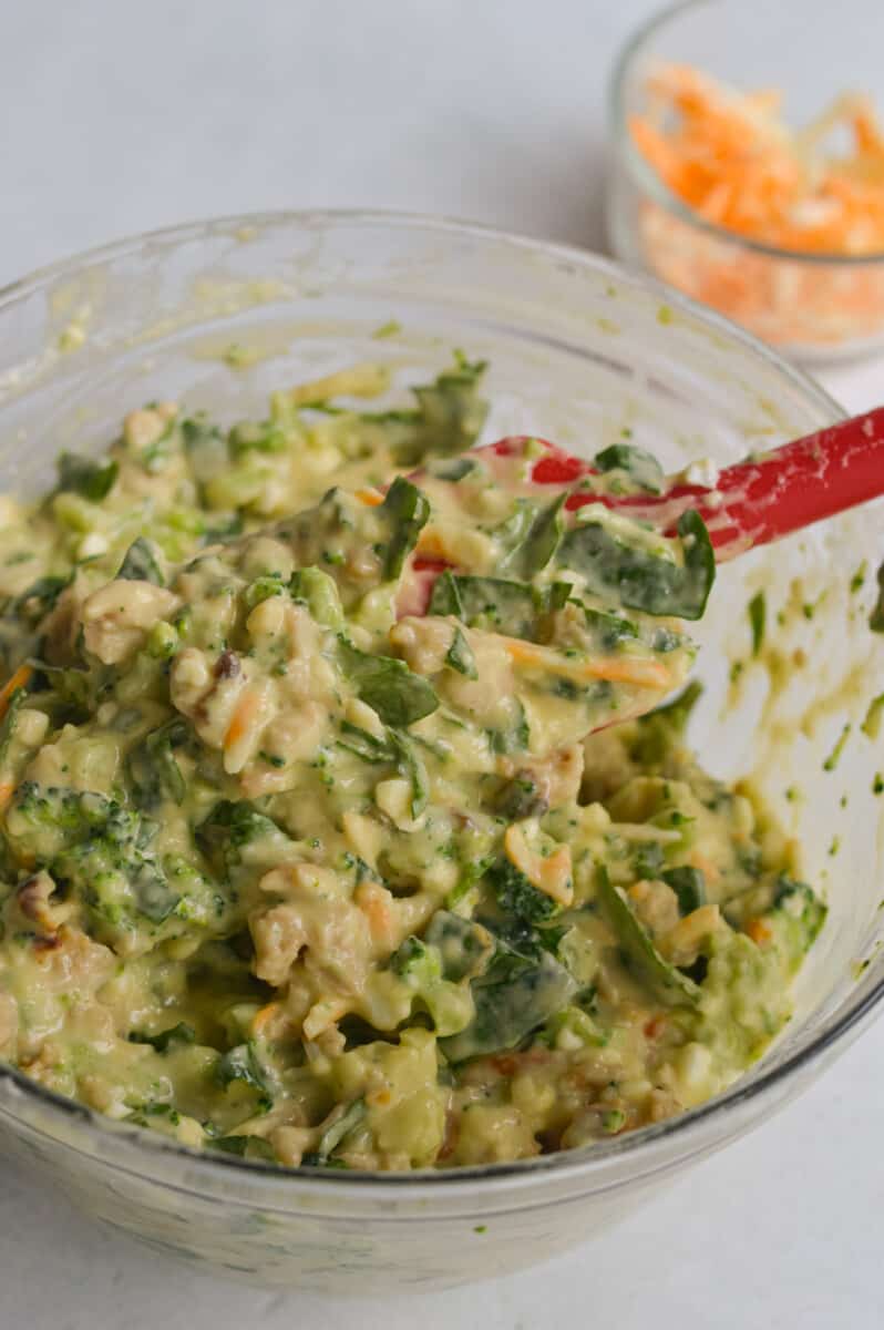 Mixing savory muffin batter after adding veggies and cooked sausage.