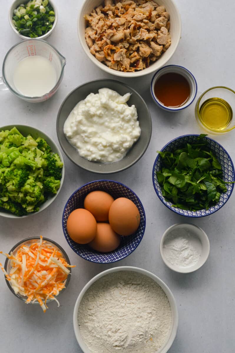 Ingredients including eggs, cottage cheese, turkey sausage, frozen spinach, broccoli, cheese, olive oil, maple syrup, baking powder, salt, milk and green onion.