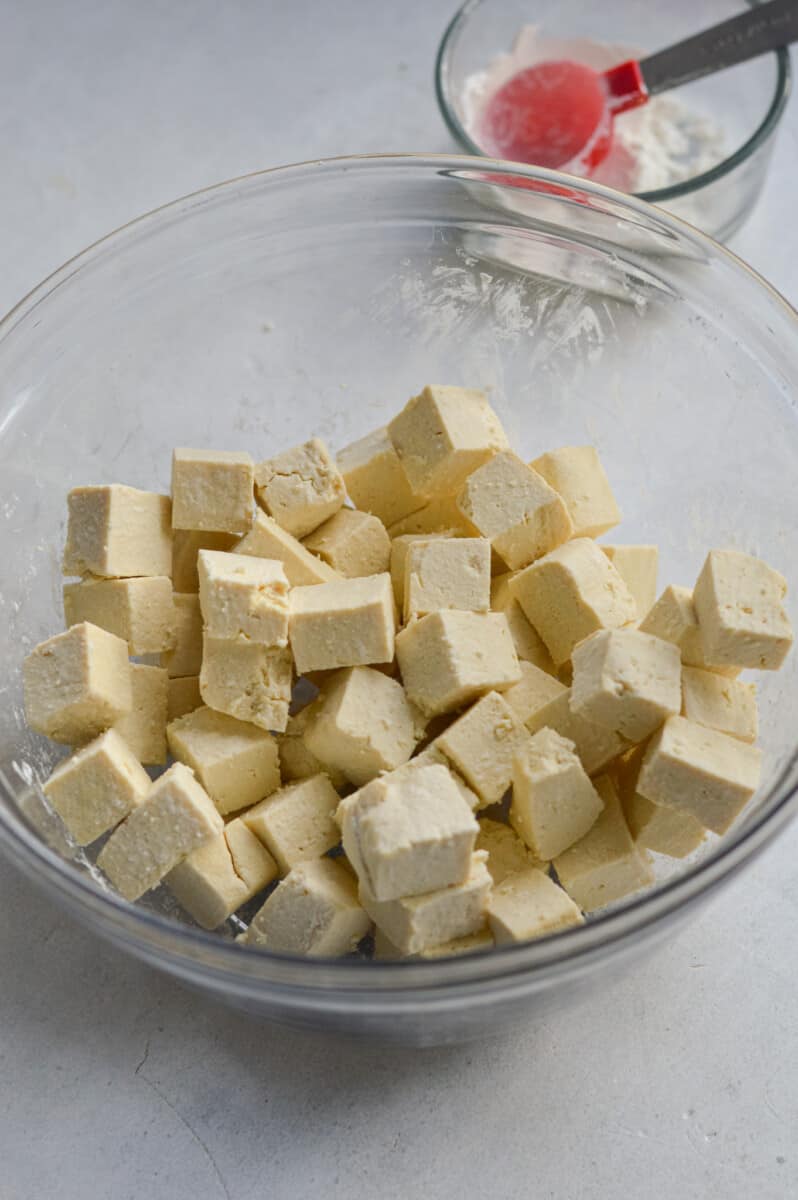 Cubed tofu in a bowl next to a cornstarch mixture.
