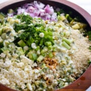 Bowl of dill pickle salad with cucumber, feta, red onion, green onion, lentils, walnuts and brown rice.