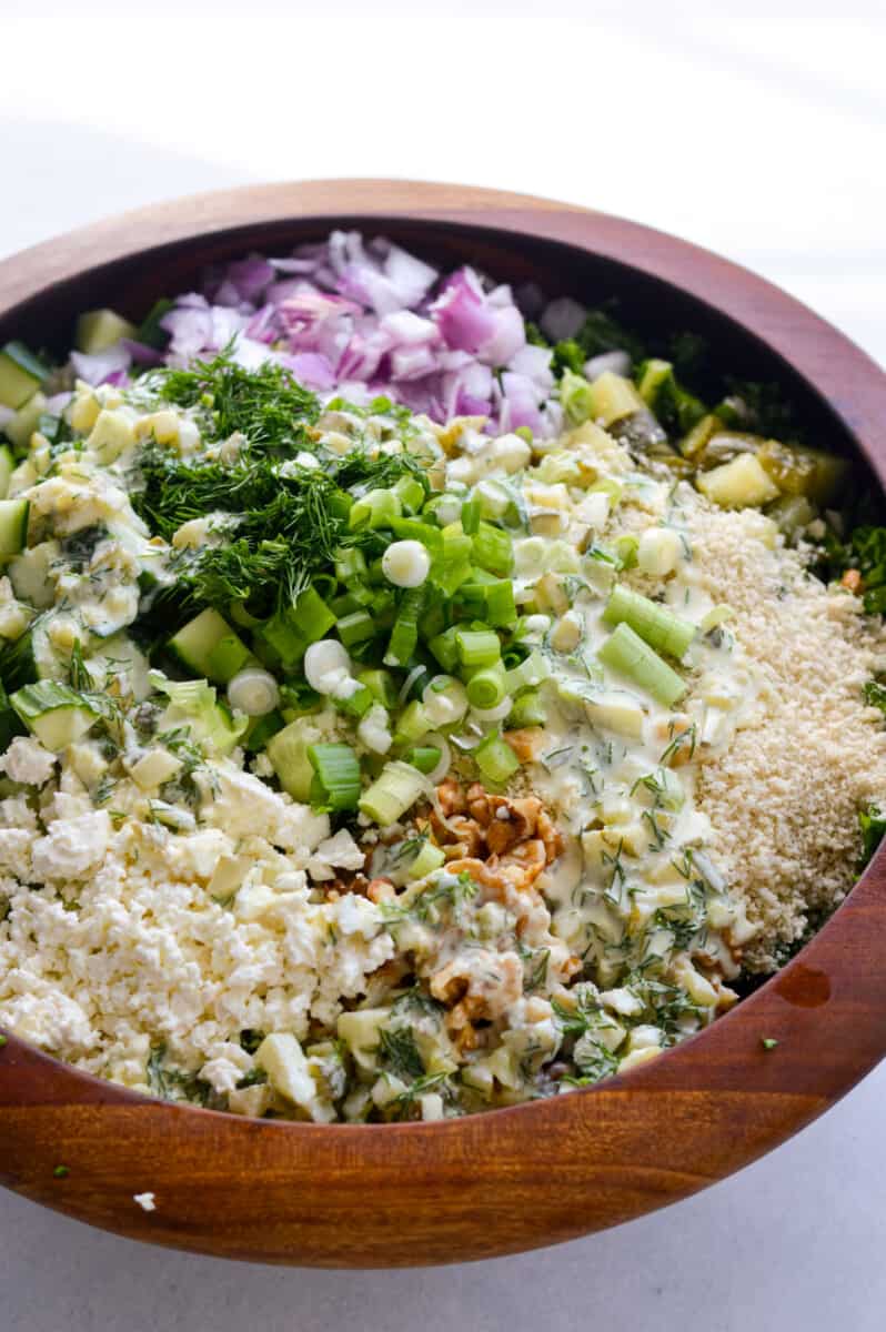 Bowl of dill pickle salad with cucumber, feta, red onion, green onion, lentils, walnuts and brown rice.
