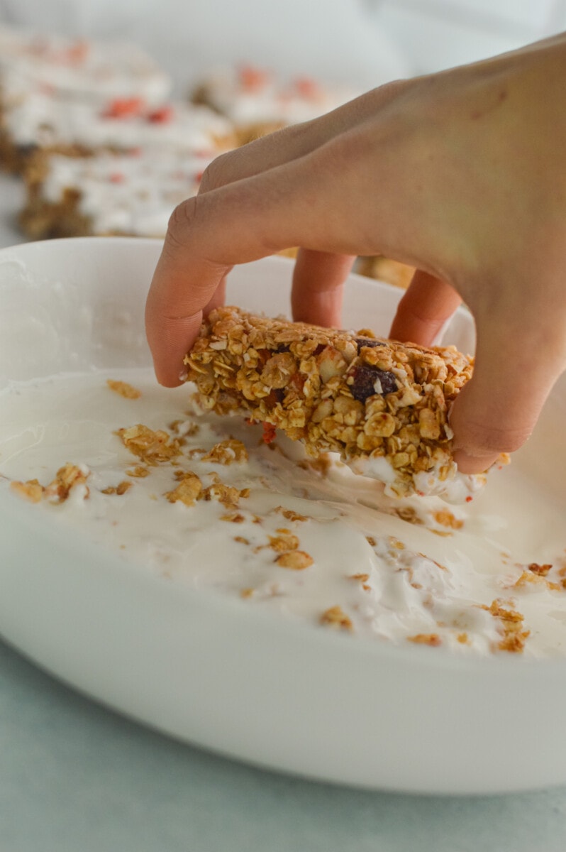Dipping granola bars into yogurt coating.