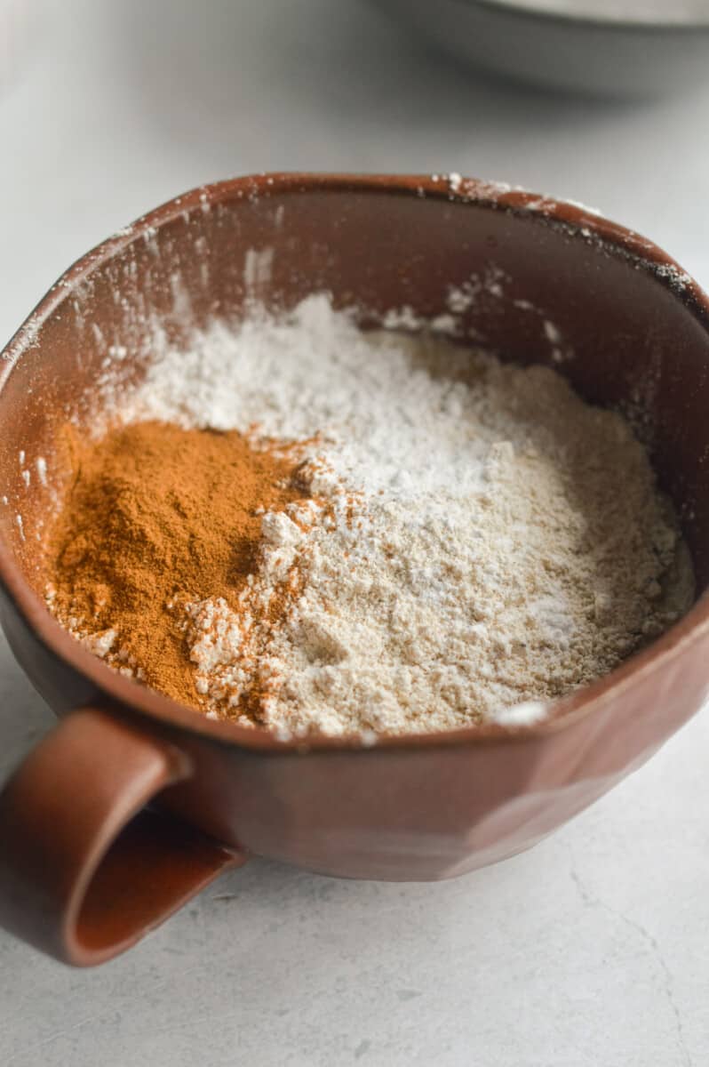 Adding oat flour, cinnamon and baking powder to wet ingredients.