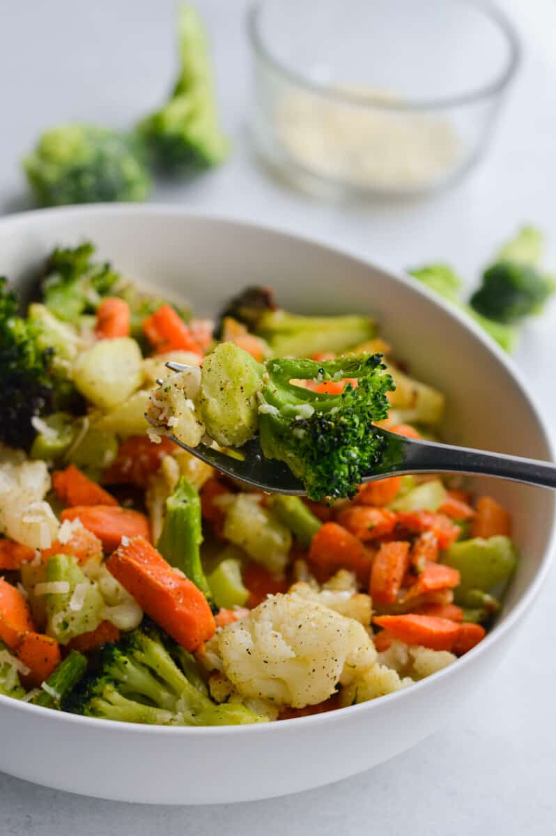 Forkful of air fryer frozen broccoli and a bowl of air fried vegetables.