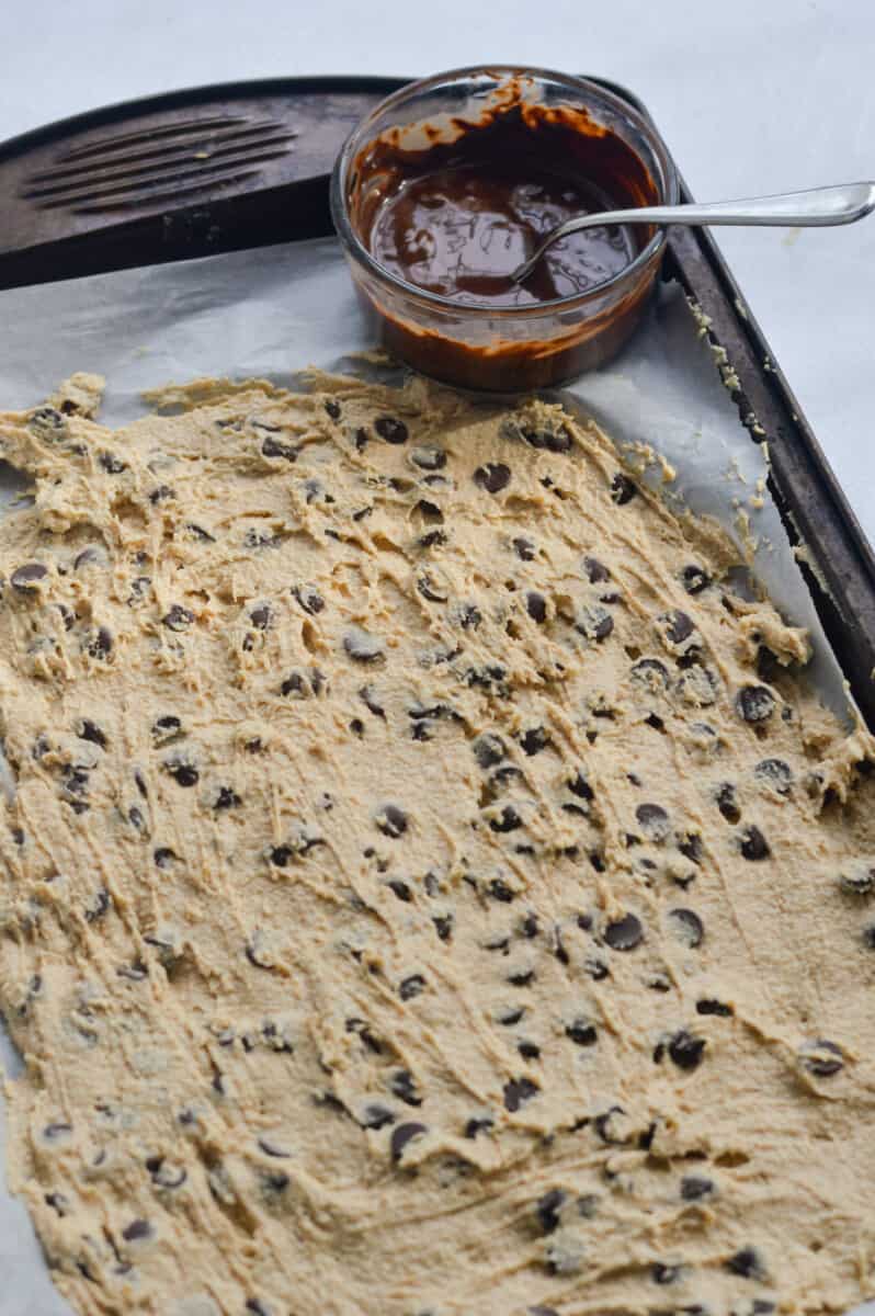 Spreading cottage cheese cookie dough on a baking sheet lined with parchment paper.