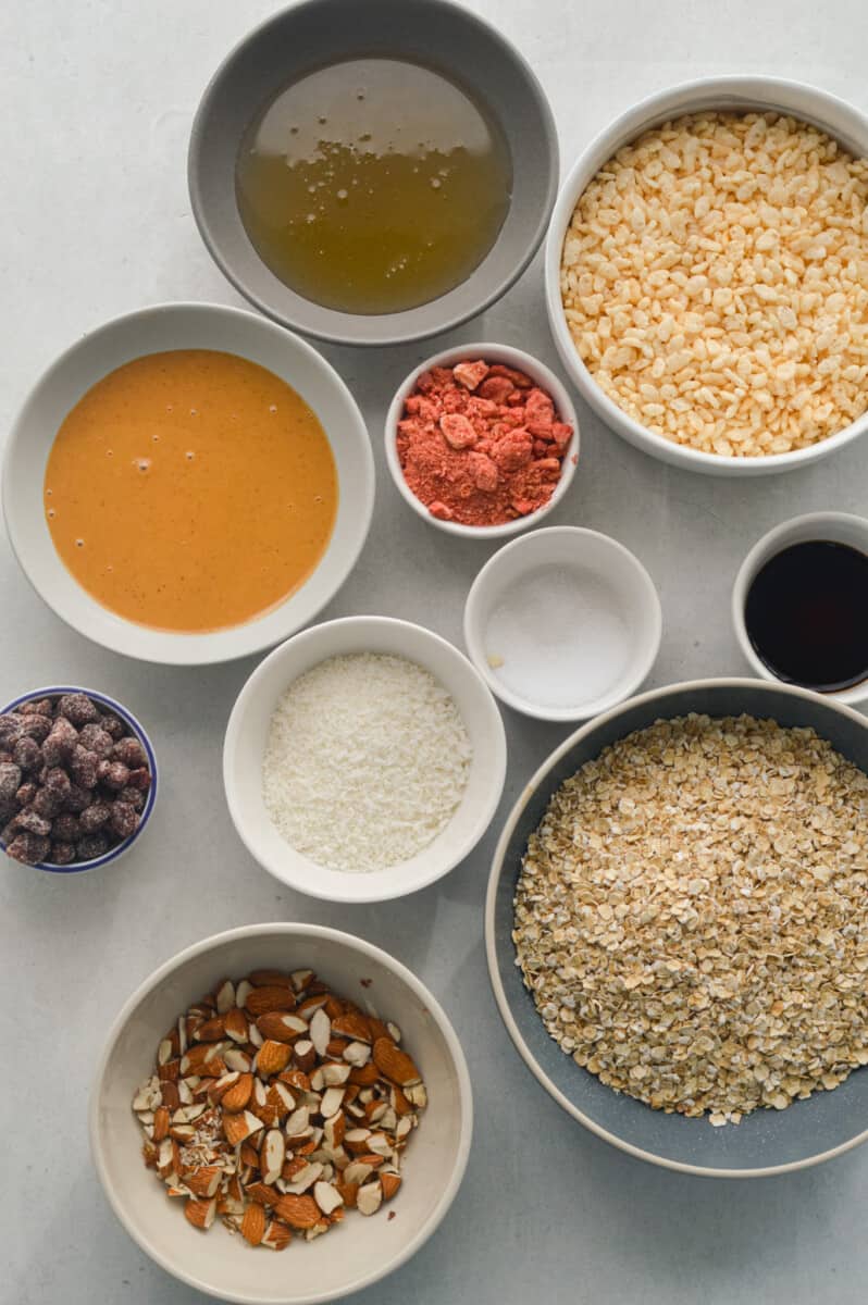 Ingredients including oats, honey, peanut butter, freeze dried strawberries, almonds, puffed rice cereal, cinnamon, vanilla and coconut.