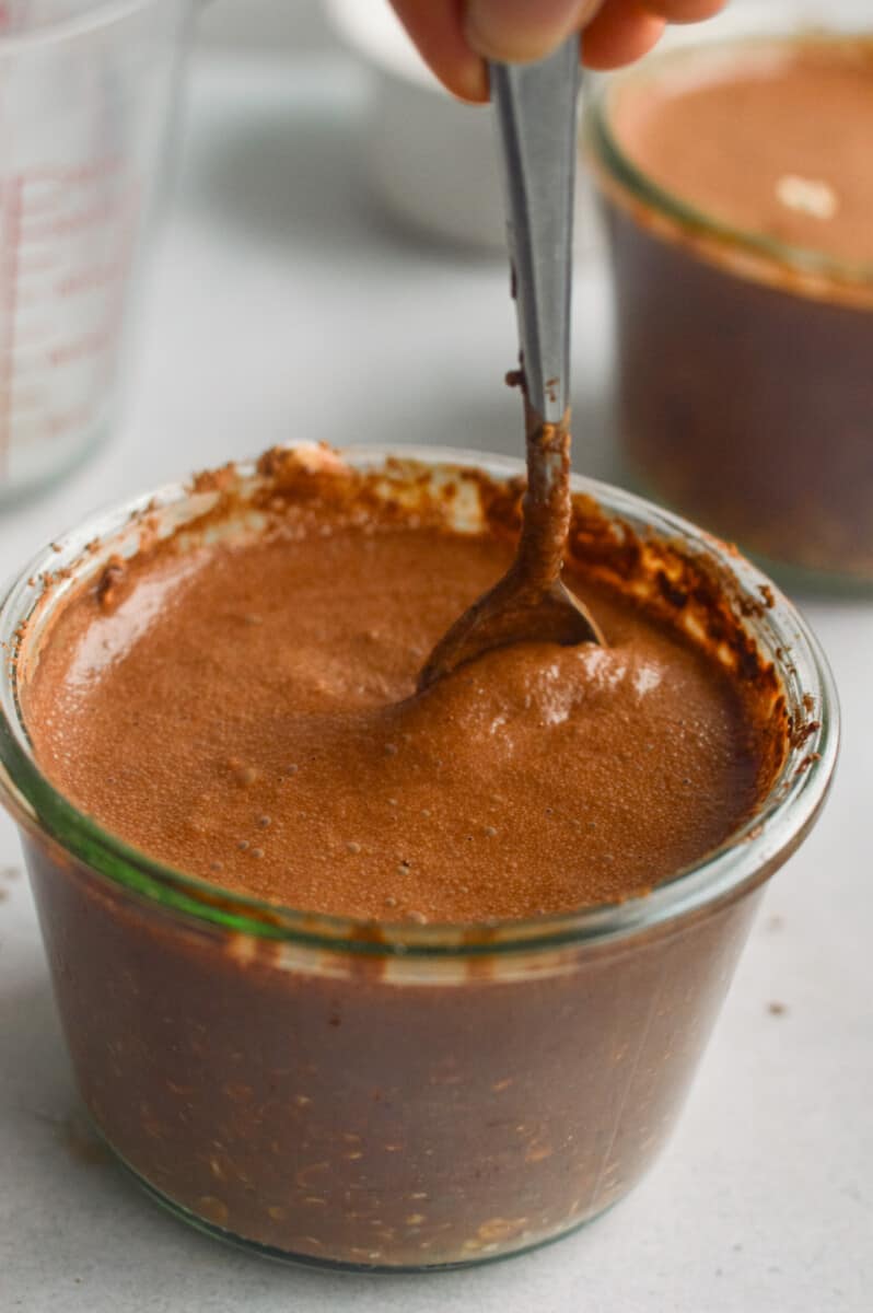 Mixing chocolate overnight oats with a spoon.