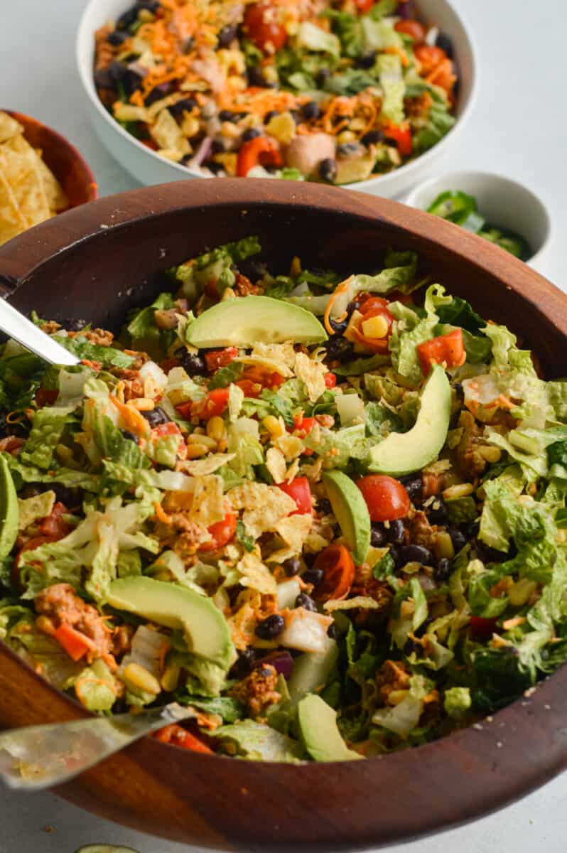 Bowl of nacho salad with ground turkey, avocado, tomatoes, cheese and tortilla chips.