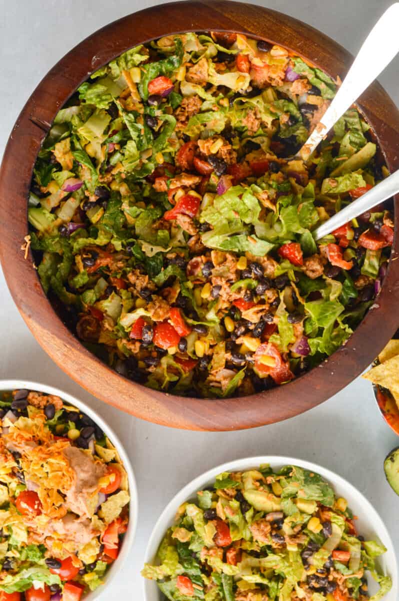Serving plates of nacho salad from a big serving bowl.