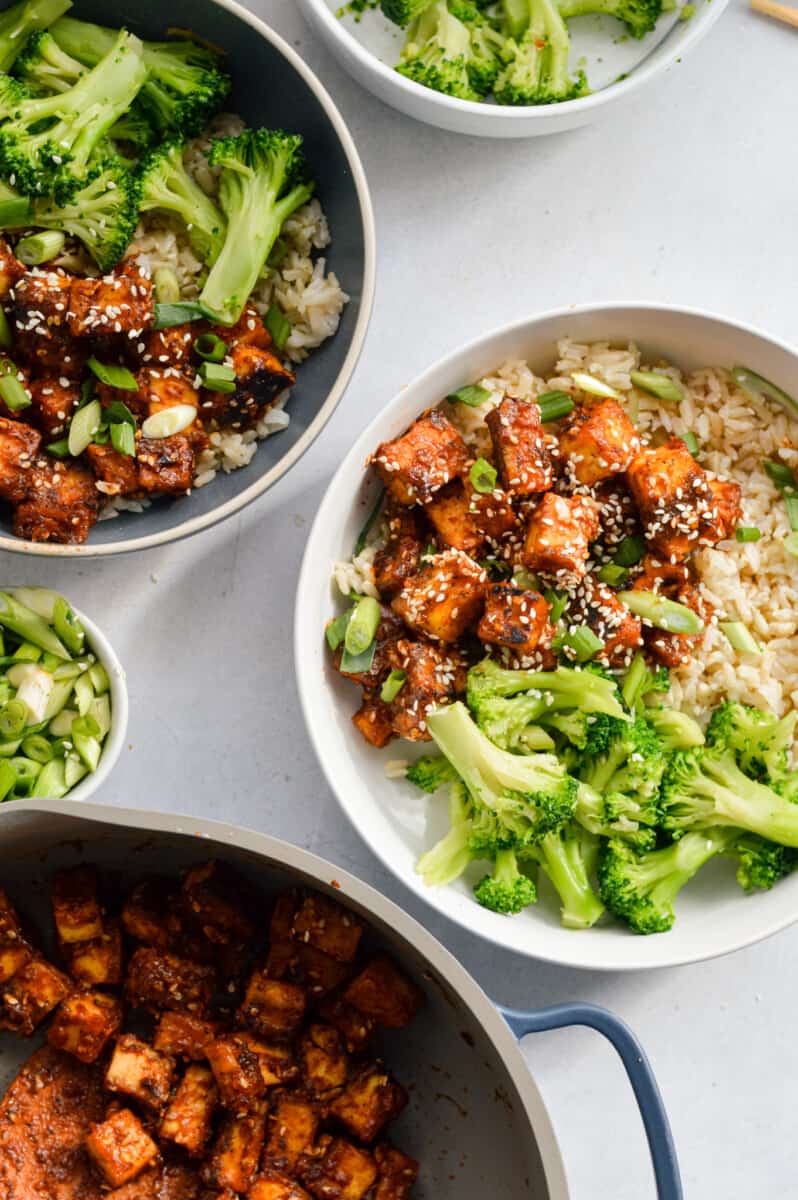 Serving sticky orange tofu bowls with brown rice, broccoli, and green onion.