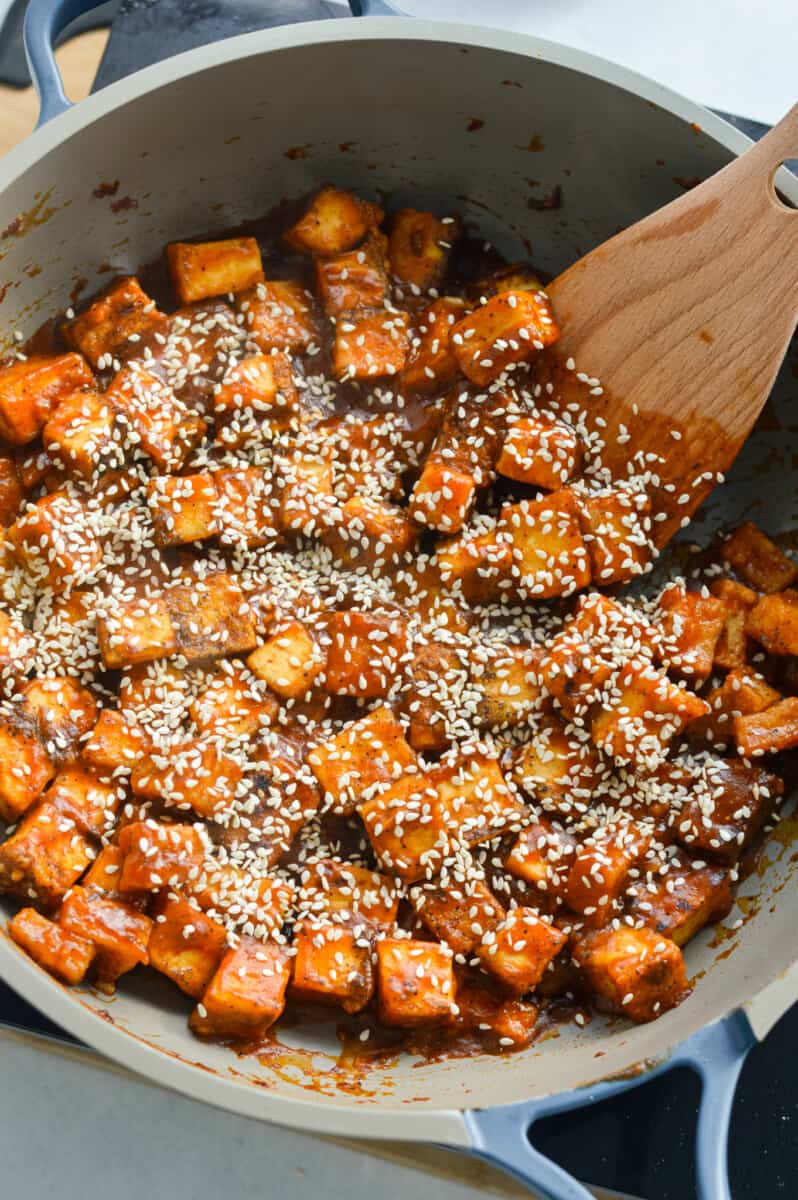Adding sesame seeds to orange tofu.