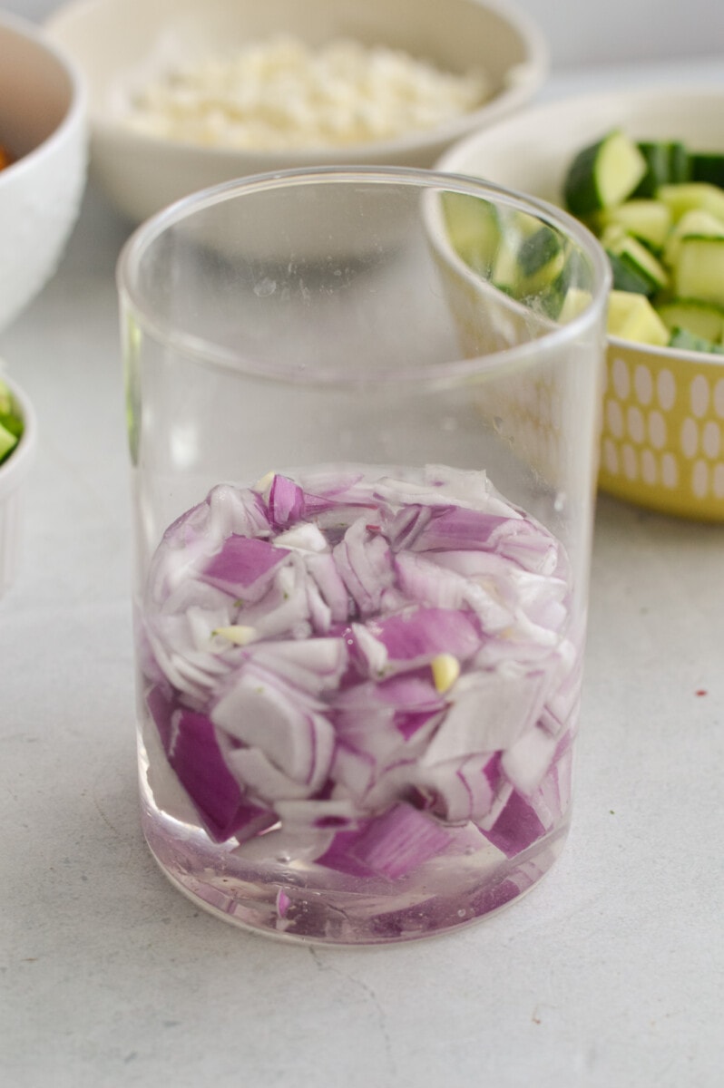 Soaking diced red onion in a glass of water.