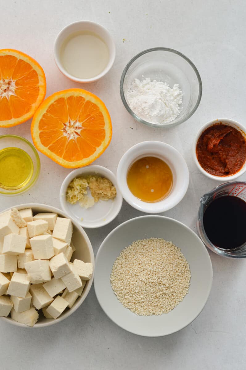 Ingredients including extra firm tofu, orange, soy sauce, tomato paste, cornstarch, garlic, ginger, olive oil and rice vinegar.