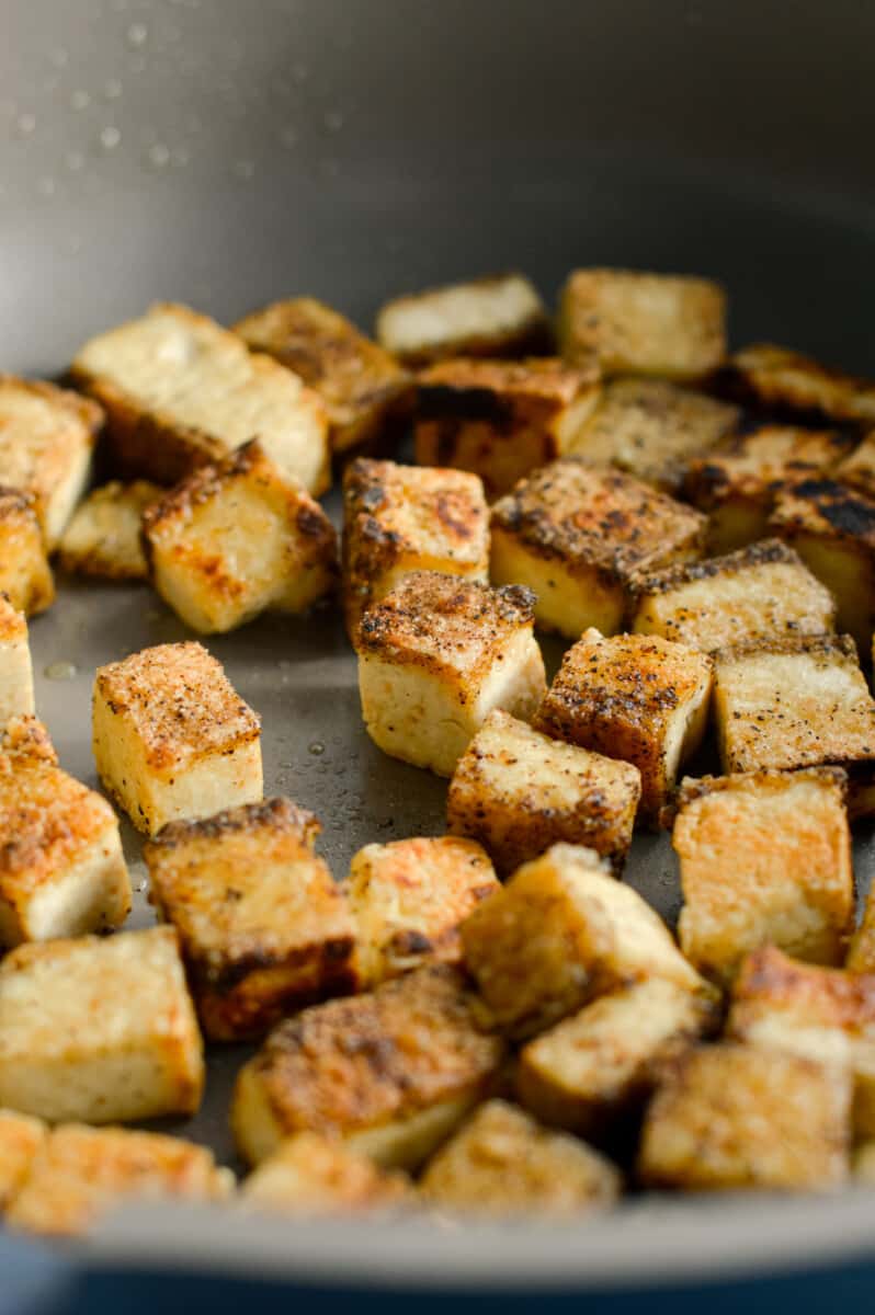 Frying cubed tofu in a pan.