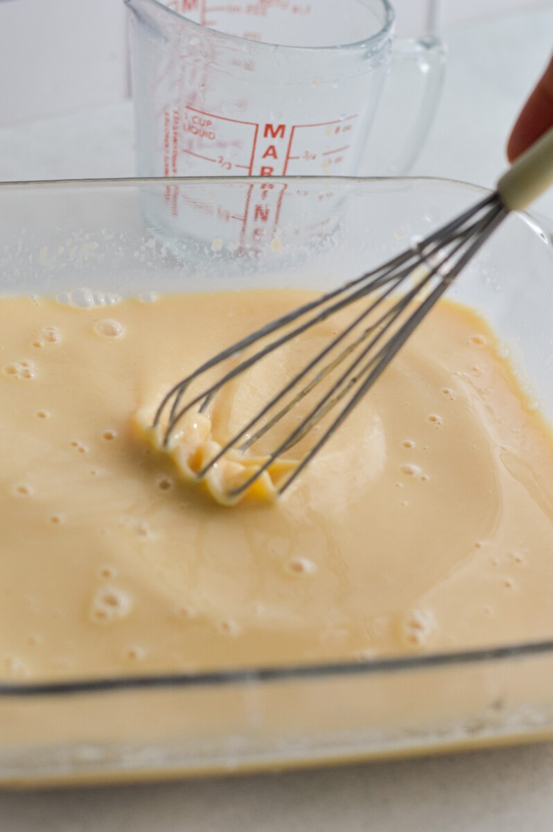 Whisking applesauce, eggs, honey, milk and vanilla extract in a baking dish.