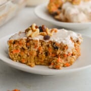 Plate with a slice of carrot cake baked oatmeal with walnuts and Greek yogurt frosting.