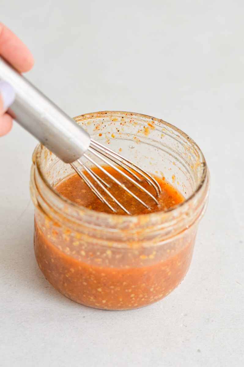 Whisking together a jar of honey mustard vinaigrette.