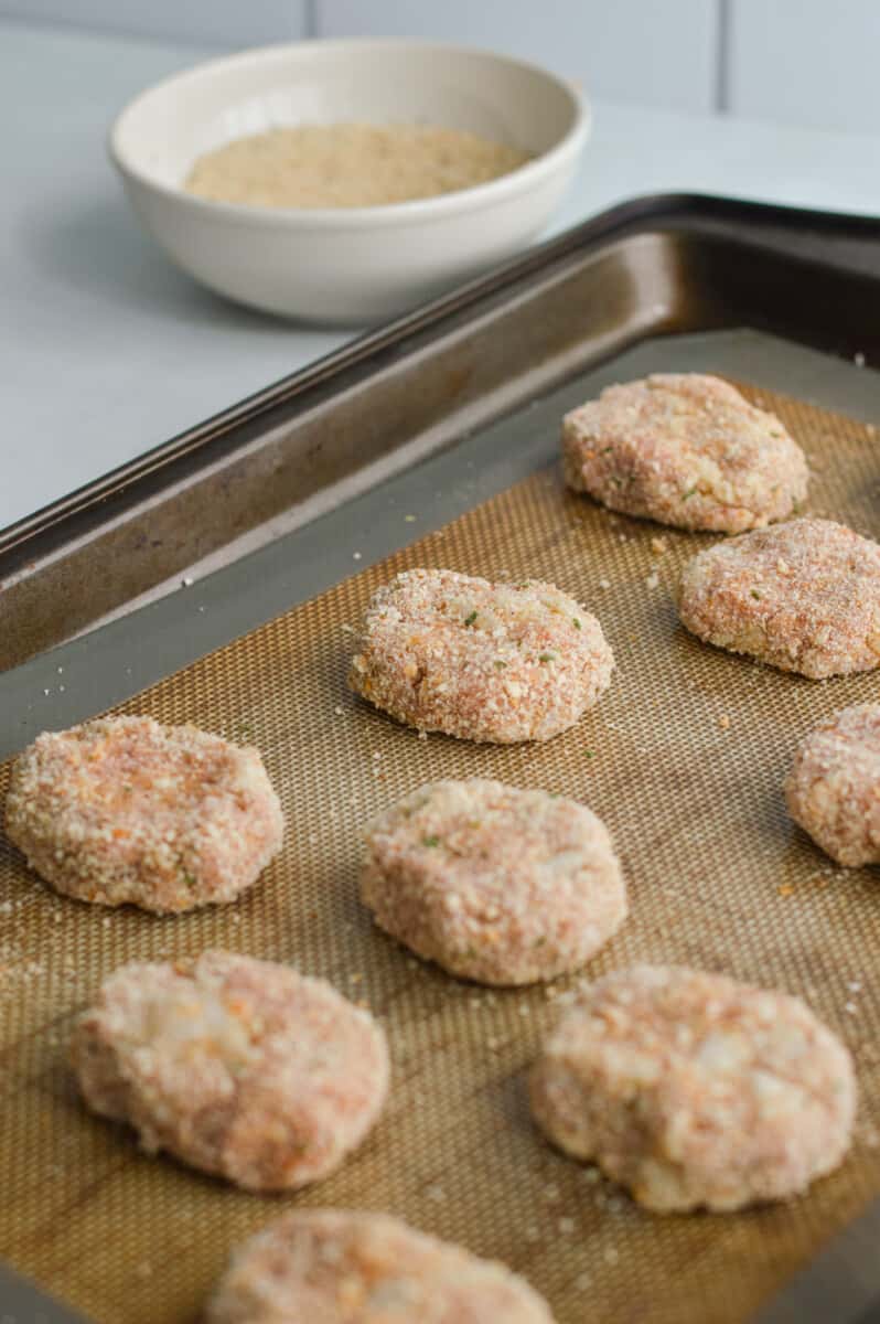 Rolling homemade ground chicken nuggets onto a tray.