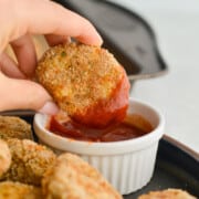 Dipping a homenade chicken nugget into a ramekin with ketchup.