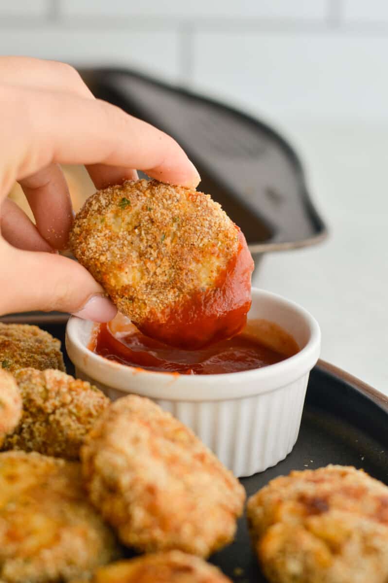 Dipping a homenade chicken nugget into a ramekin with ketchup.