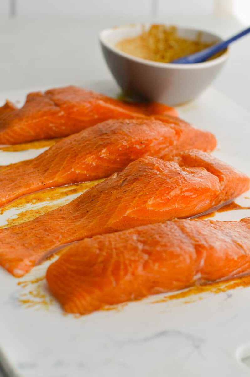 Brushing olive oil and spices on salmon fillets.