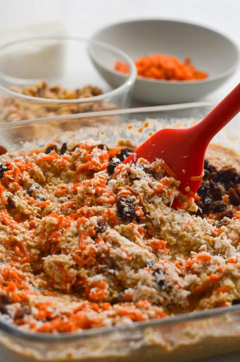 Folding carrots, raisins, walnuts and coconut into baked oatmeal batter.