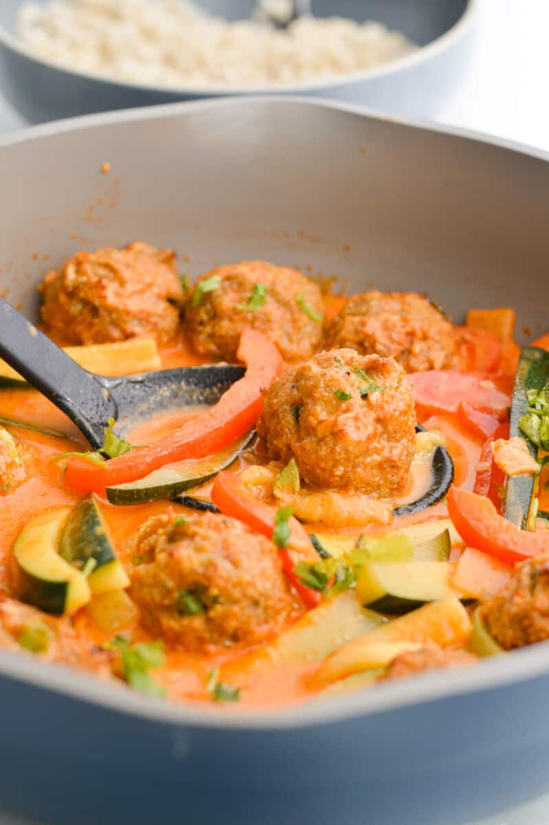 Pan of red Thai curry with ginger chicken meatballs.