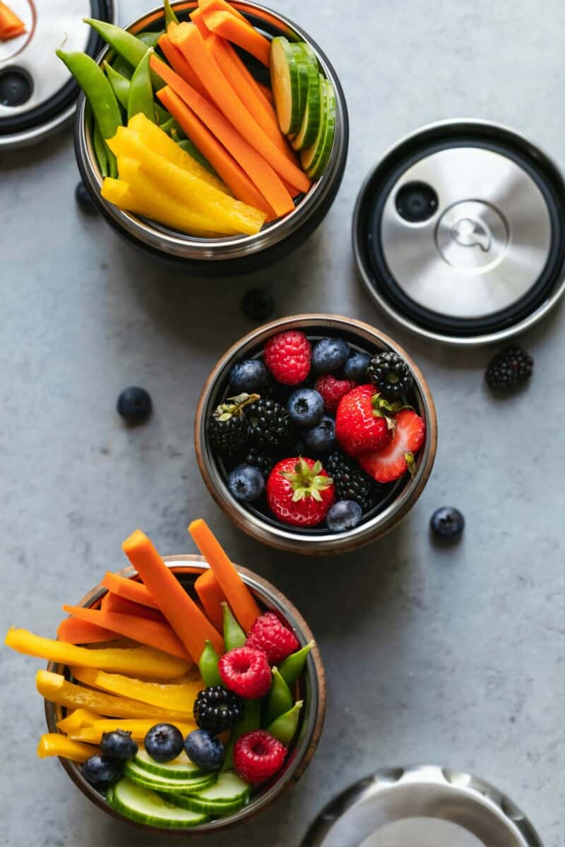 Plates of healthy snacks like berries and cut-up vegetables.