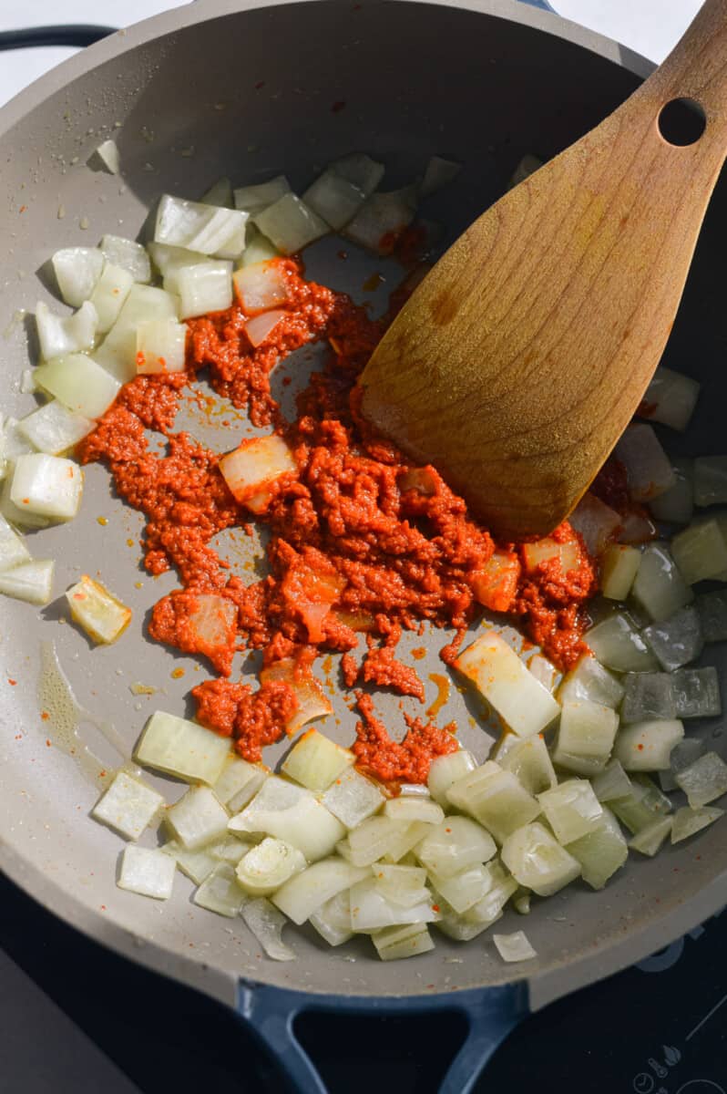 Sauteeing onions in red curry paste.