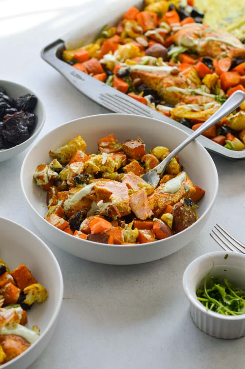 Serving a bowl of Moroccan salmon and vegetables.