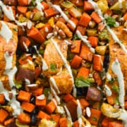 Drizzling yogurt sauce on sheet pan moroccan salmon and vegetables.