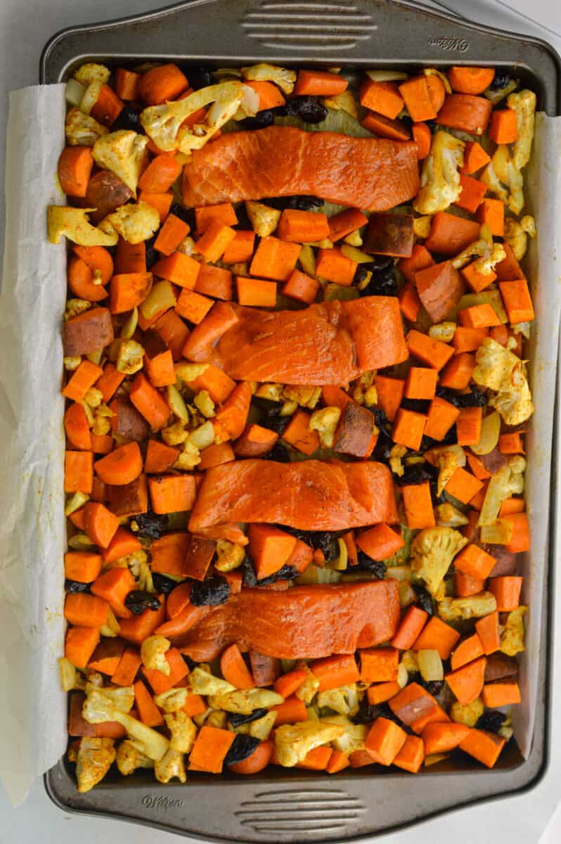 Birds eye of sheet pan with roasted cauliflower, carrots and sweet potato with salmon fillets.