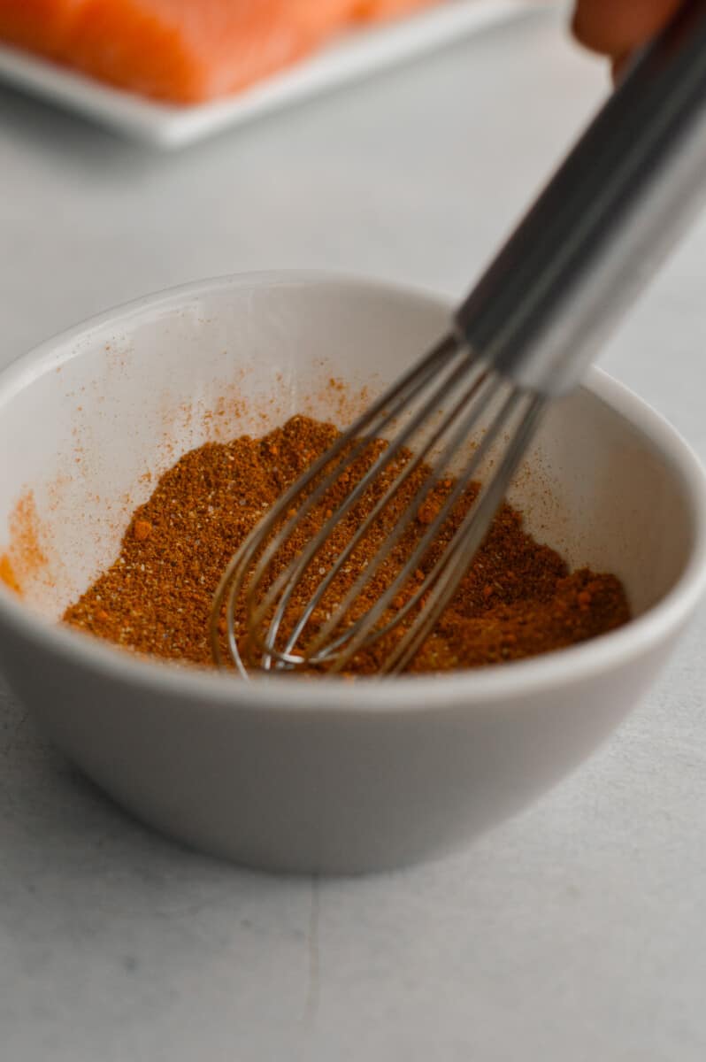Mixing spices including turmeric, cumin, garlic powder, paprika, cinnamon, black pepper and salt.