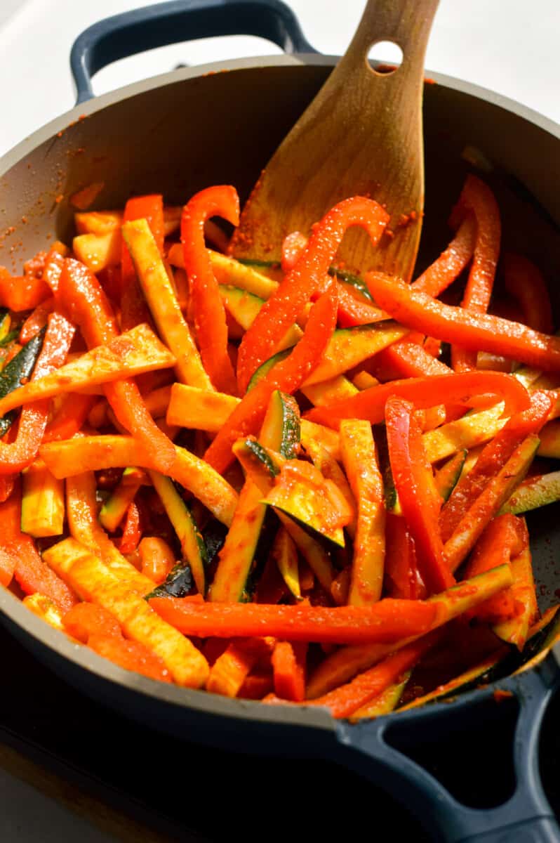 Stir frying vegetables in red curry paste.