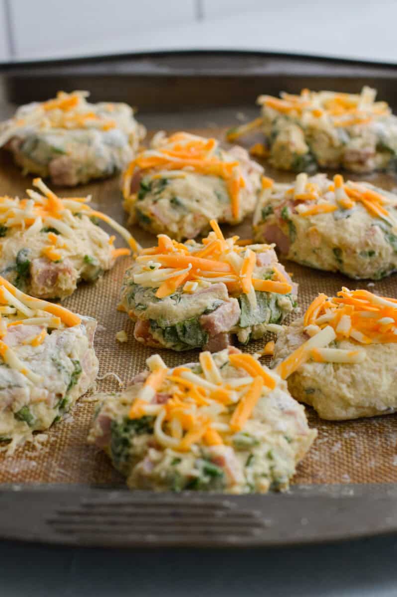 Sprinkling cheese on top of protein biscuits.