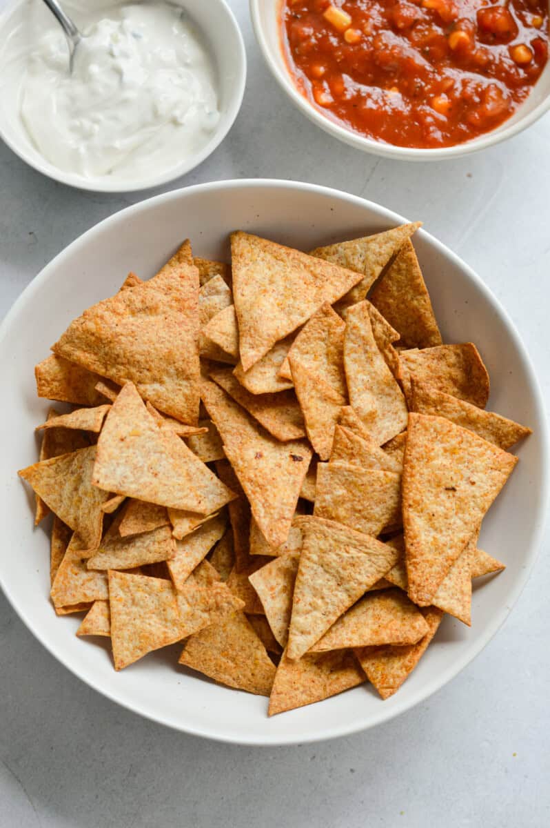 Bowl of air fryer tortilla chips, served with dip and salsa.