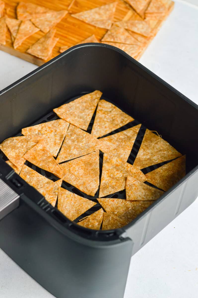 Placing tortilla chips in the air fryer.