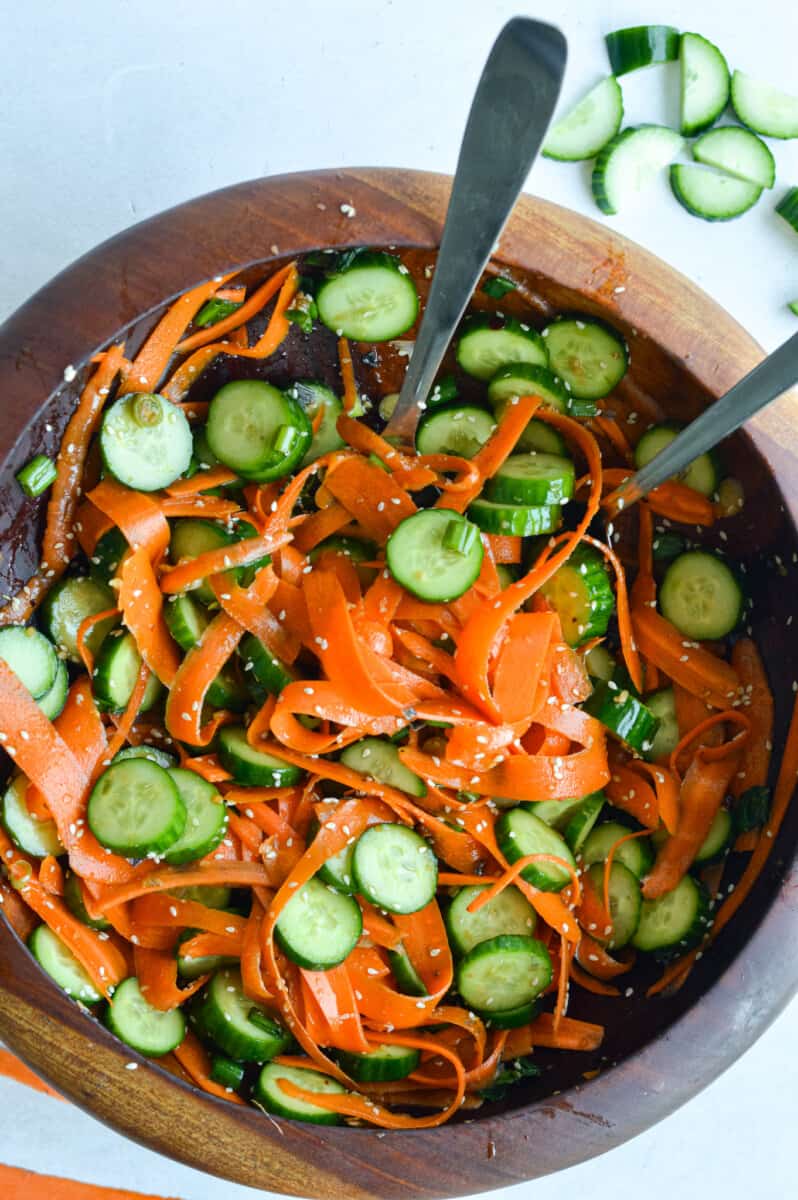 Birds eye of a cucumber and carrot salad in a brown wooden salad bowl.